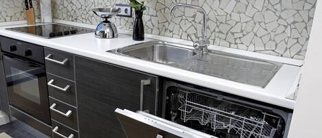 A modern kitchen with a stainless steel sink, a dishwasher, and a tiled backsplash.