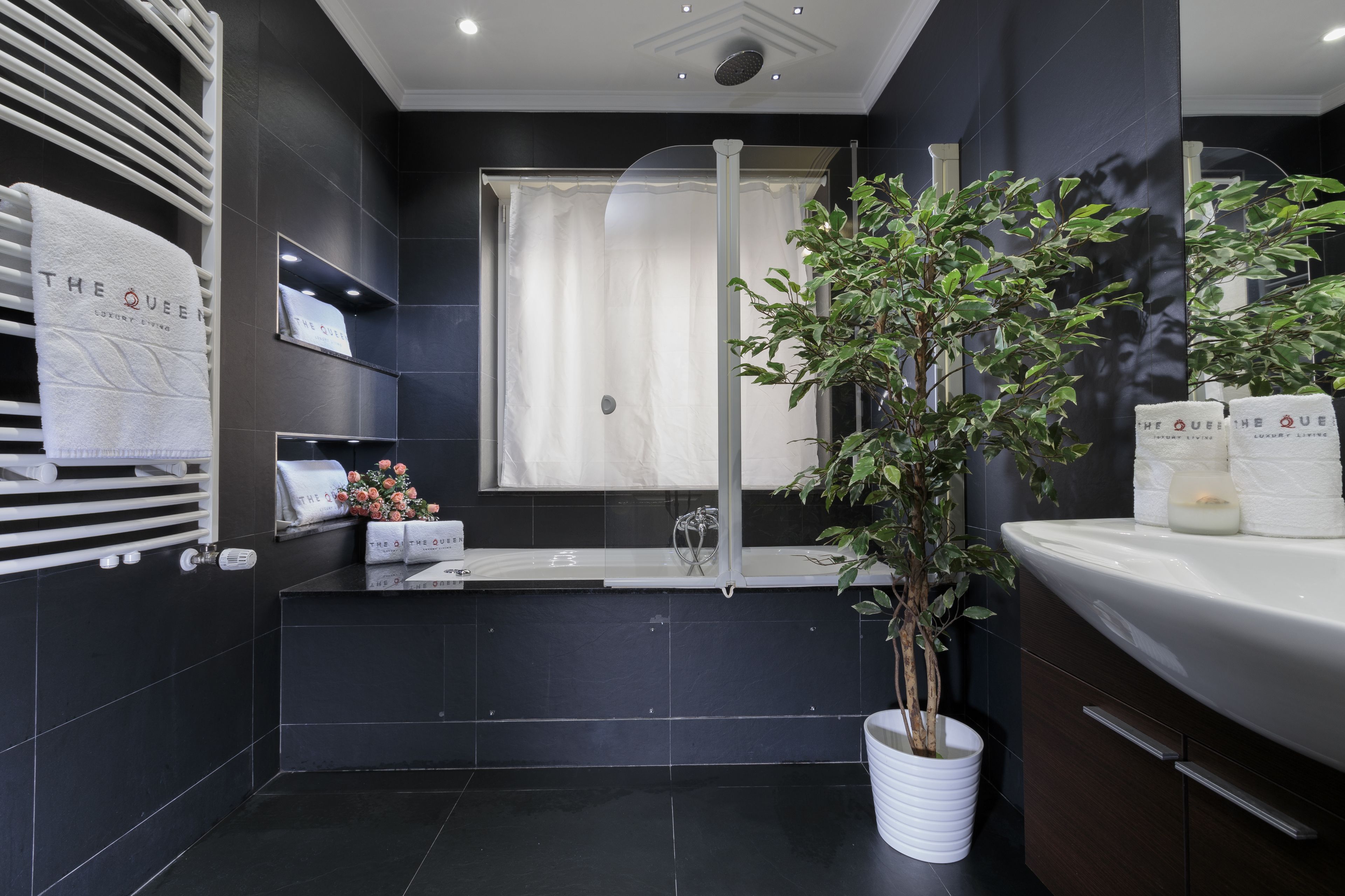 A modern bathroom with a bathtub, a shower, and a large potted plant.