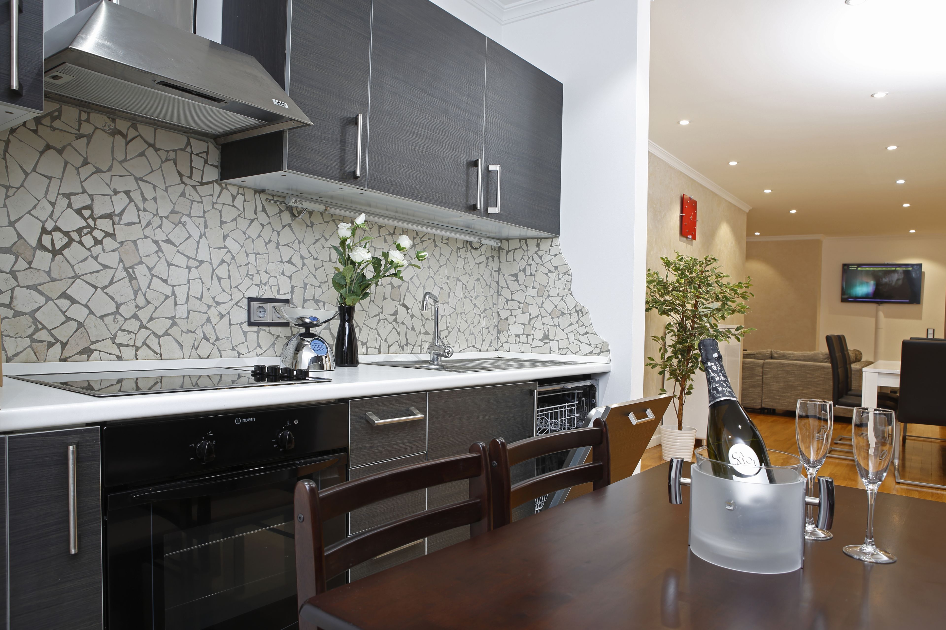 Una cocina moderna con protector contra salpicaduras de piedra, electrodomésticos de acero inoxidable y un comedor con una mesa preparada para dos.