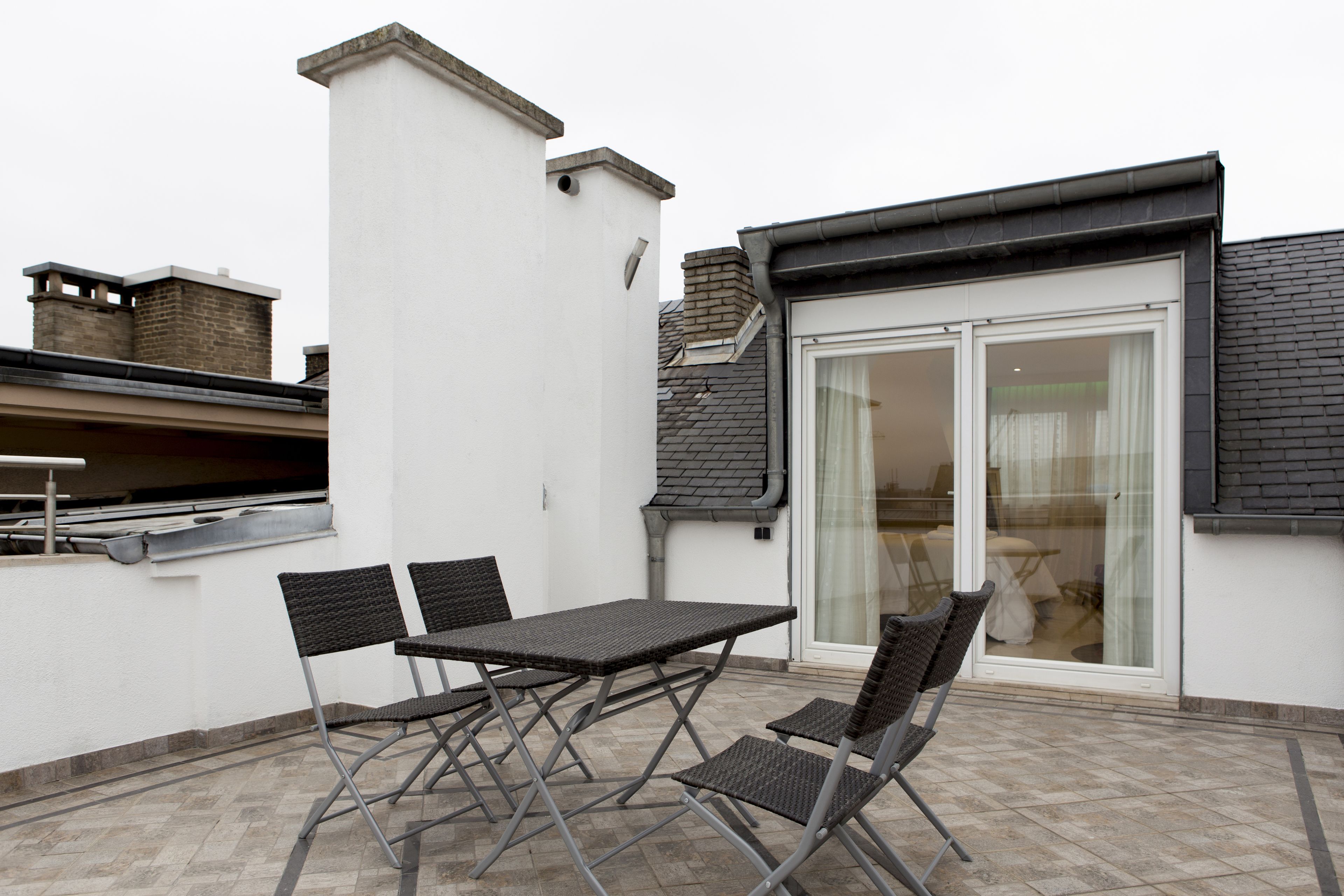 A patio with a table and chairs, a sliding glass door, and a chimney.
