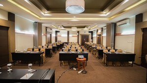 A conference room with multiple tables, chairs, and a podium, equipped with microphones and a laptop. - Sofyan Hotel Soepomo (Jakarta)