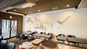 A cafe interior with tables, chairs, and a wall mural. - Sofyan Hotel Soepomo (Jakarta)