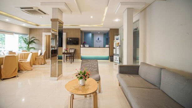 A hotel reception area with a reception desk, seating area, and a large window. - Sofyan Hotel Soepomo (Jakarta)