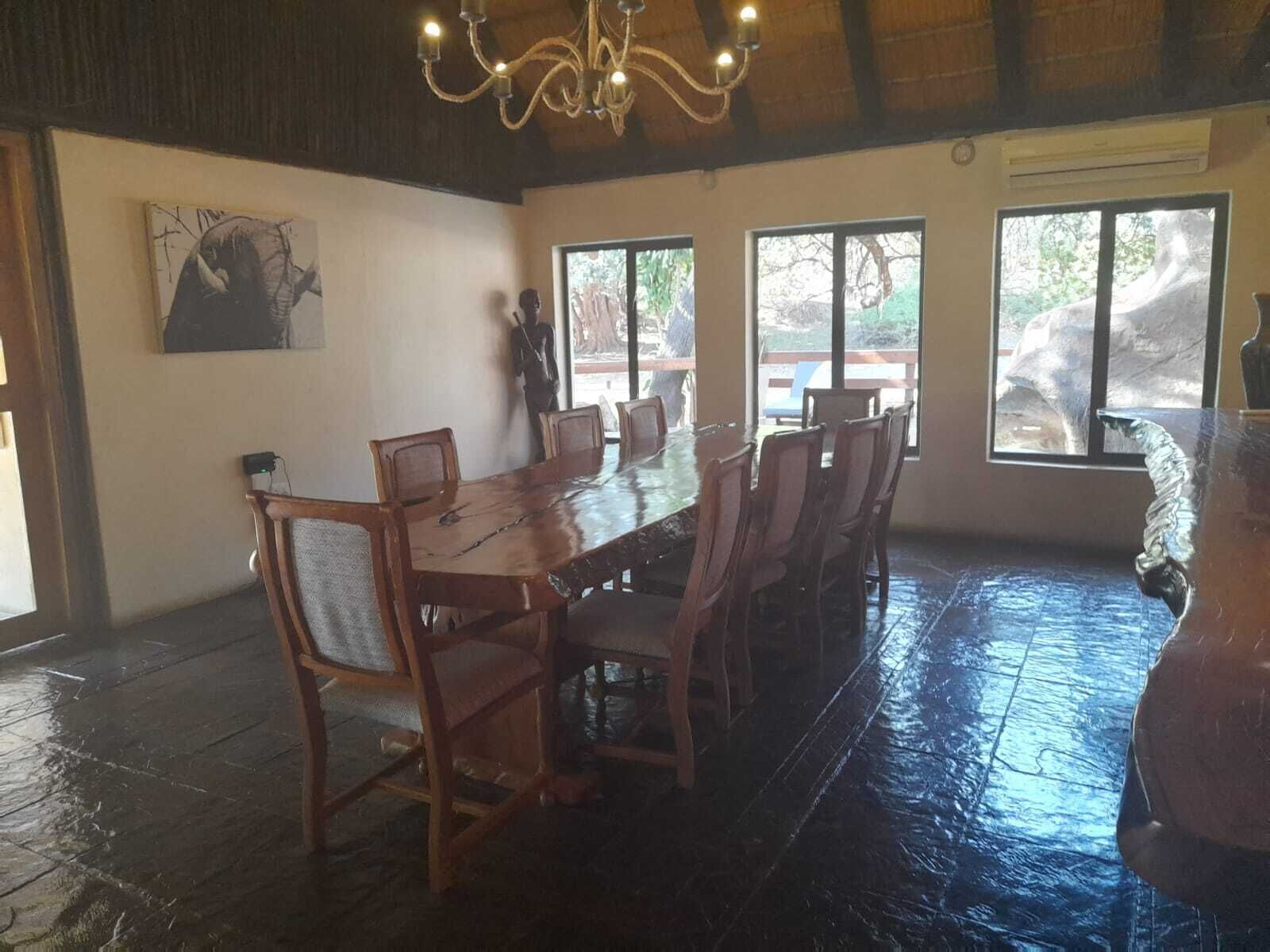 Un comedor con una larga mesa de madera y sillas, ventanas amplias y una araña.