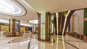 A spacious lobby with a polished marble floor, a reception area, and a seating area with sofas.