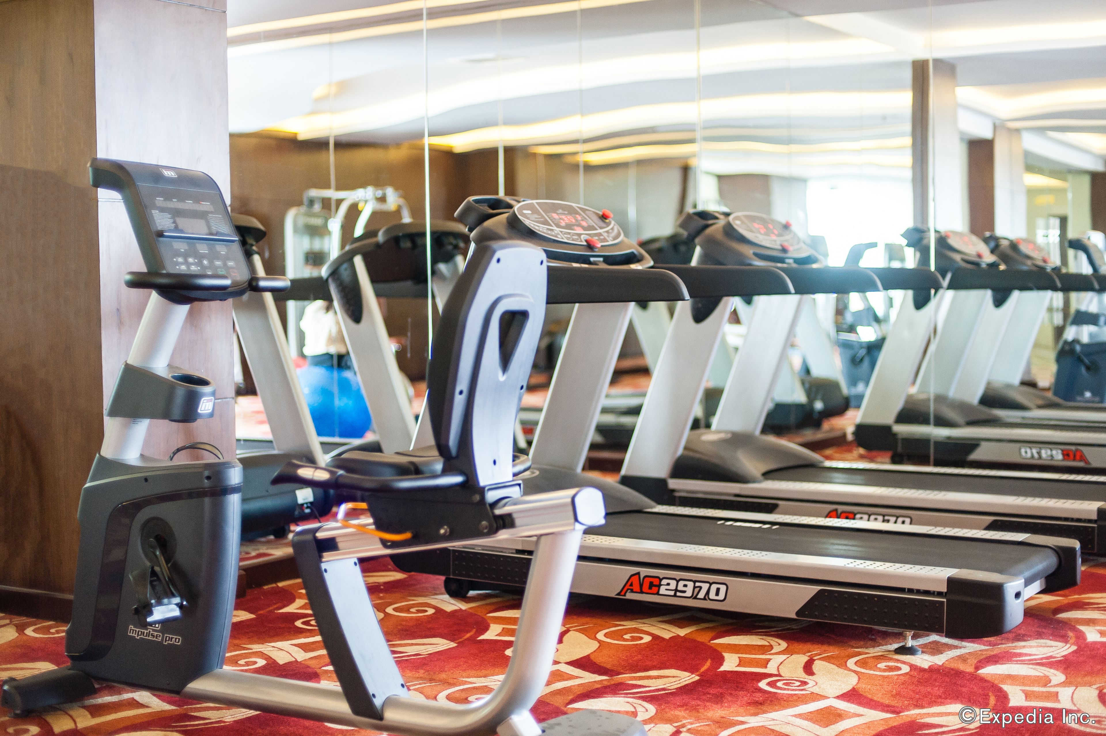A row of treadmills in a gym with a patterned carpet.