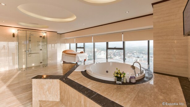 A modern bathroom with a large bathtub, a glass shower enclosure, and a view of the city.