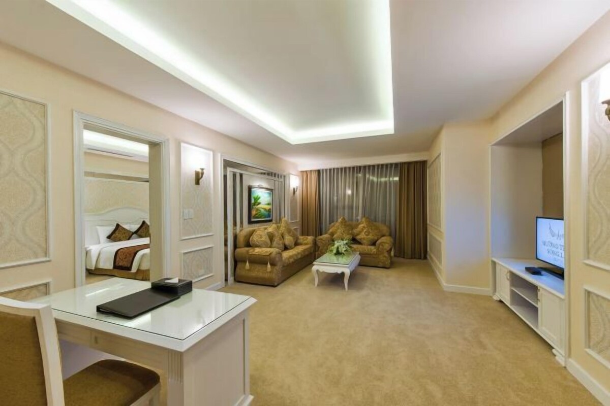 Una habitación de hotel con una cama, dos sofás, una mesa de centro, un televisor y un escritorio con una silla.