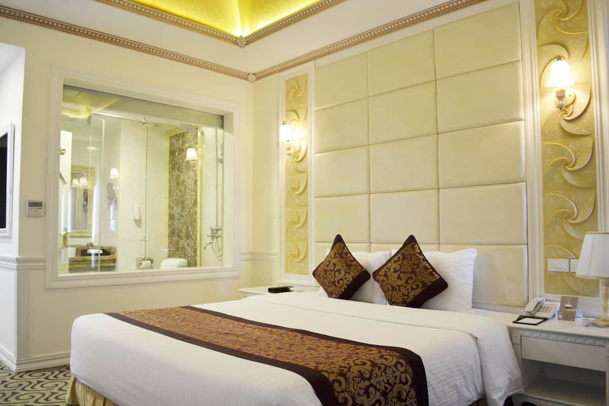Een hotelkamer met een groot bed, een spiegel, een nachtkastje en een wand met decoratieve panelen.