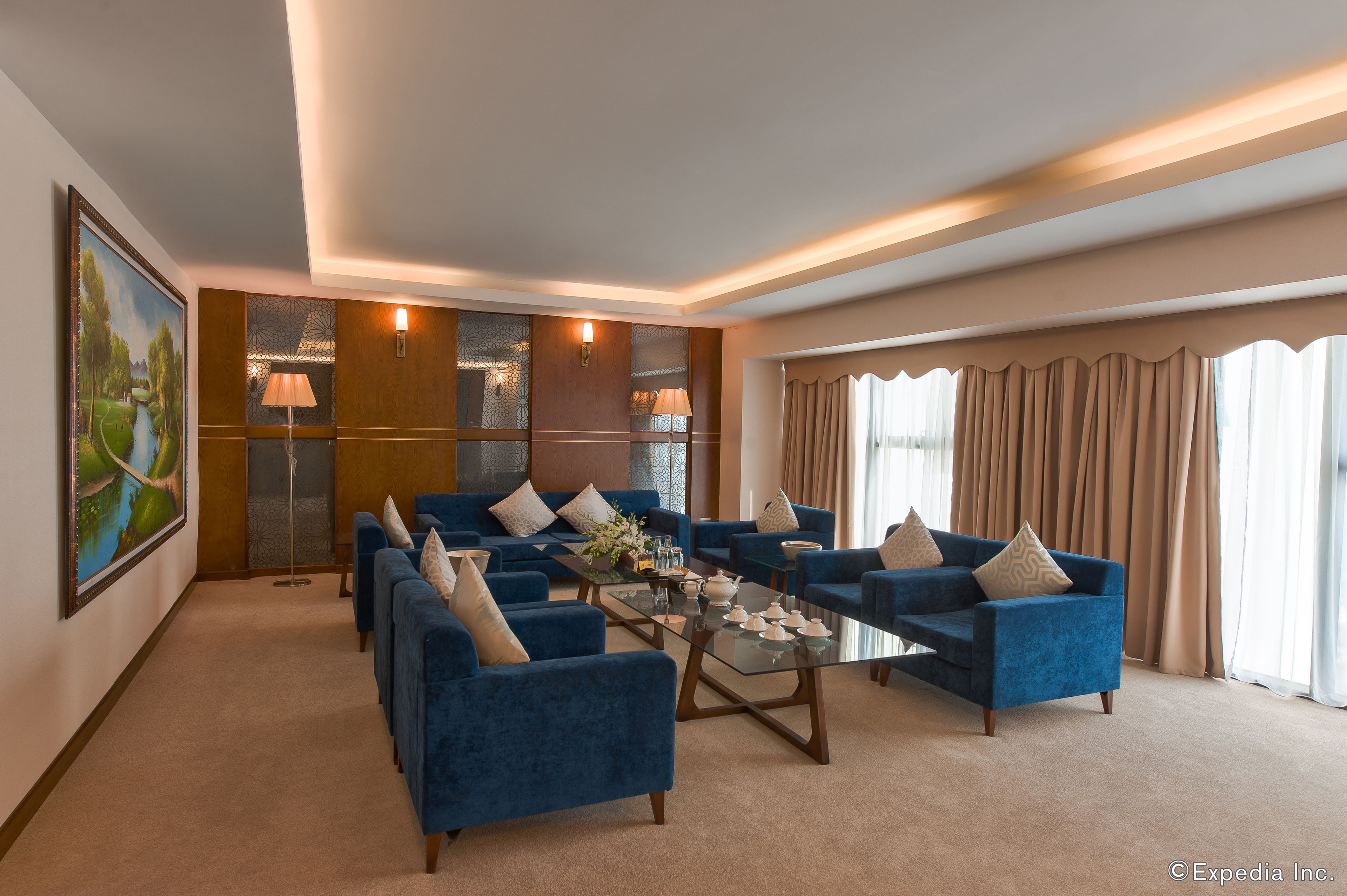 A spacious living room with a large sofa set, a coffee table, and a painting on the wall.