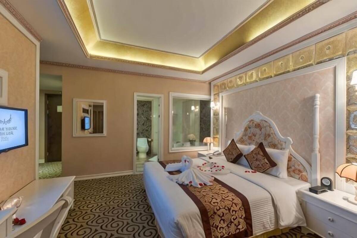 Een hotelkamer met een groot bed, een televisie, een bureau en een spiegel.