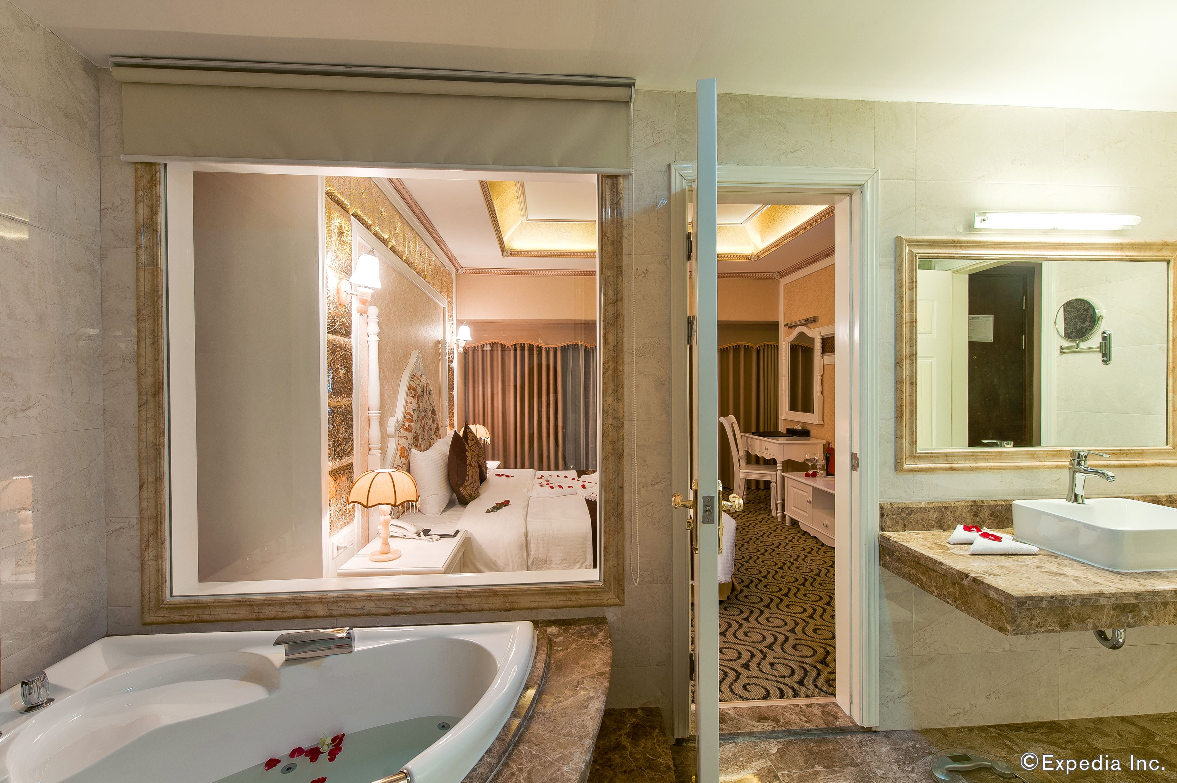 A hotel bathroom with a large bathtub, a separate sink, and a mirror.