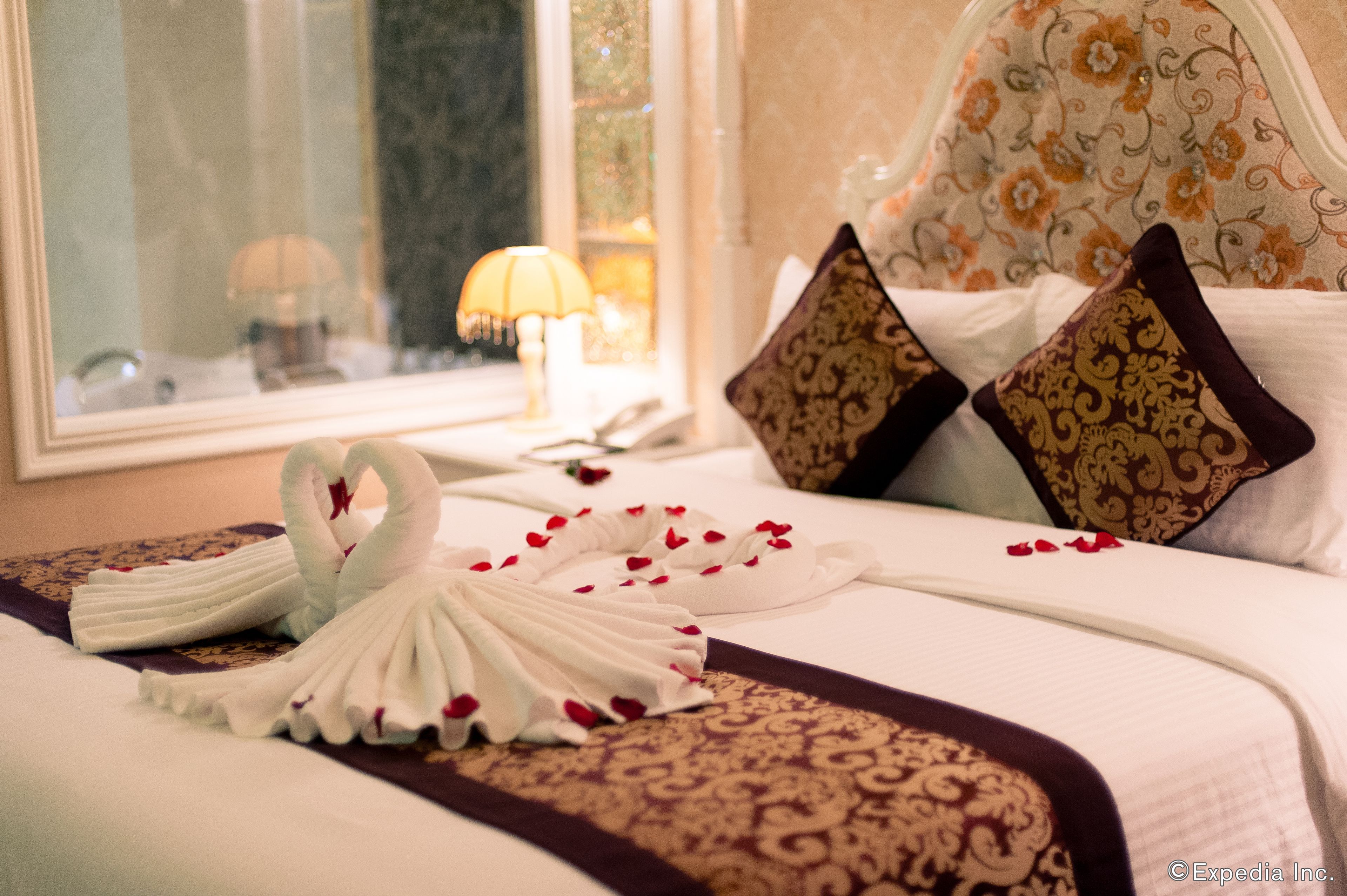 A neatly made bed with a decorative towel arrangement and a floral-patterned bedspread.
