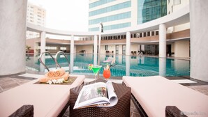 A poolside lounge with a magazine, towels, and drinks.