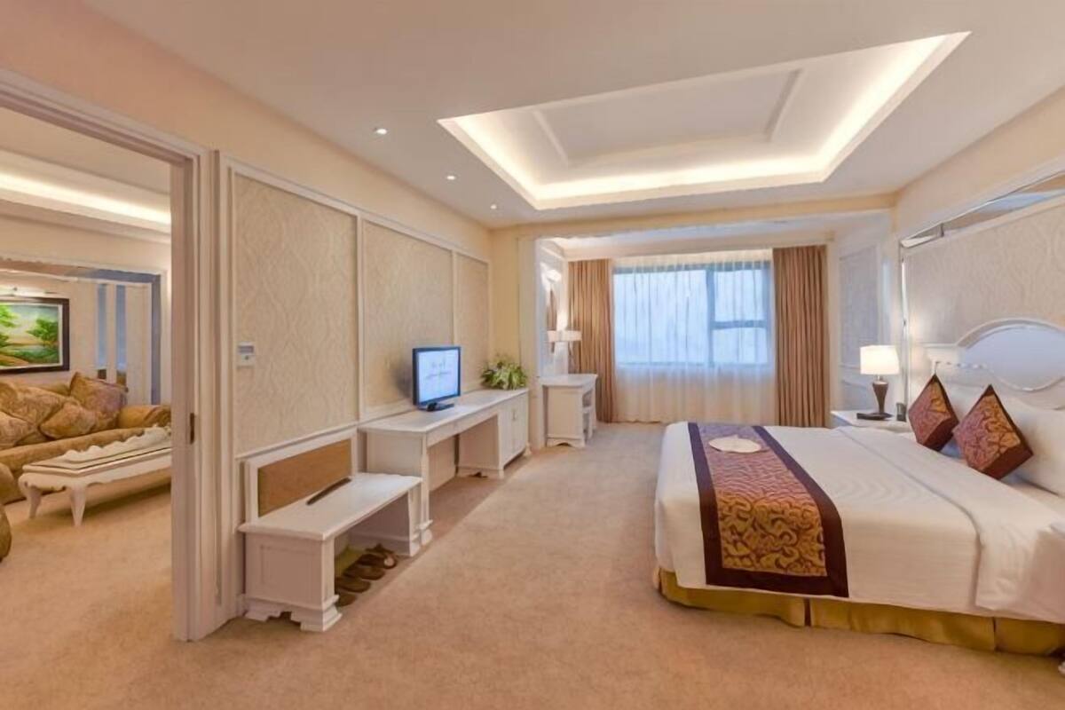 Een hotelkamer met een groot bed, een bureau, een televisie en een zithoek.