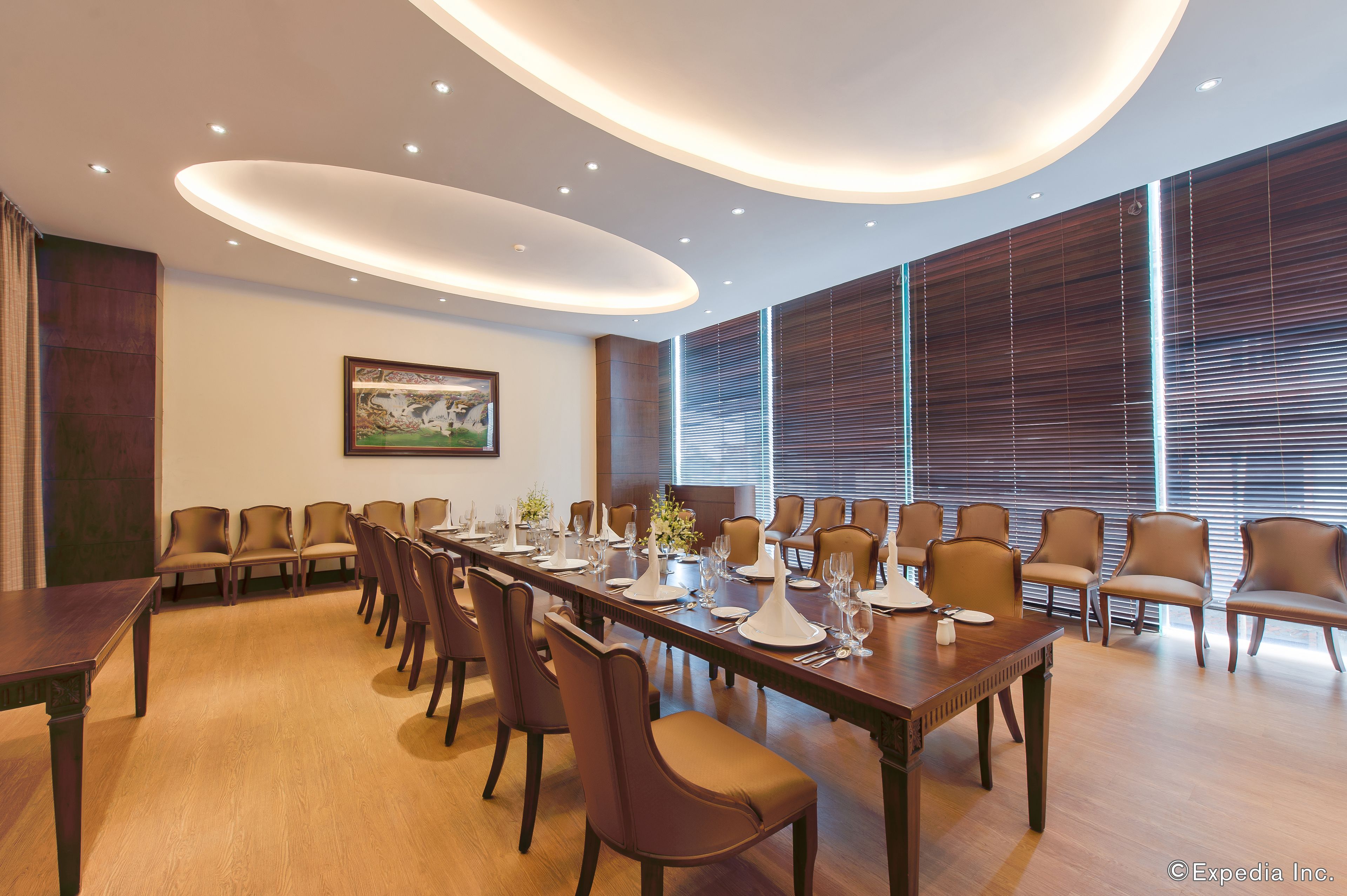 A conference room with a long table, chairs, and a painting on the wall.