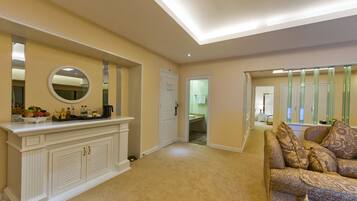 Una sala de estar con alfombra color beige, una chimenea blanca con un espejo arriba y un sofá estampado.