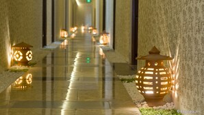 A corridor with patterned walls and a reflective floor, lined with decorative lanterns.