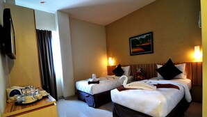 A hotel room with two beds, a desk with a tray of breakfast items, a television, and a painting on the wall. - Rangkayo Basa Halal Hotel (Padang)