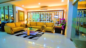 A modern living room with sofas, a coffee table, and a decorative partition. - Rangkayo Basa Halal Hotel (Padang)
