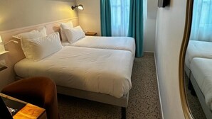 A hotel room with two beds, a desk, a chair, a ceiling fan, and a large mirror. - Trendy Canette Hotel (Paris)