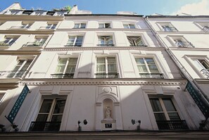 A multi-story building with a classical architectural style, featuring a central entrance with a statue, multiple balconies, and a sign indicating the building's name. - Trendy Canette Hotel (Paris)