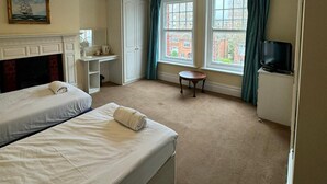 A hotel room with two beds, a desk, a chair, a television, and a window with curtains. - Langford Hotel, Brighton & Hove (Hove)