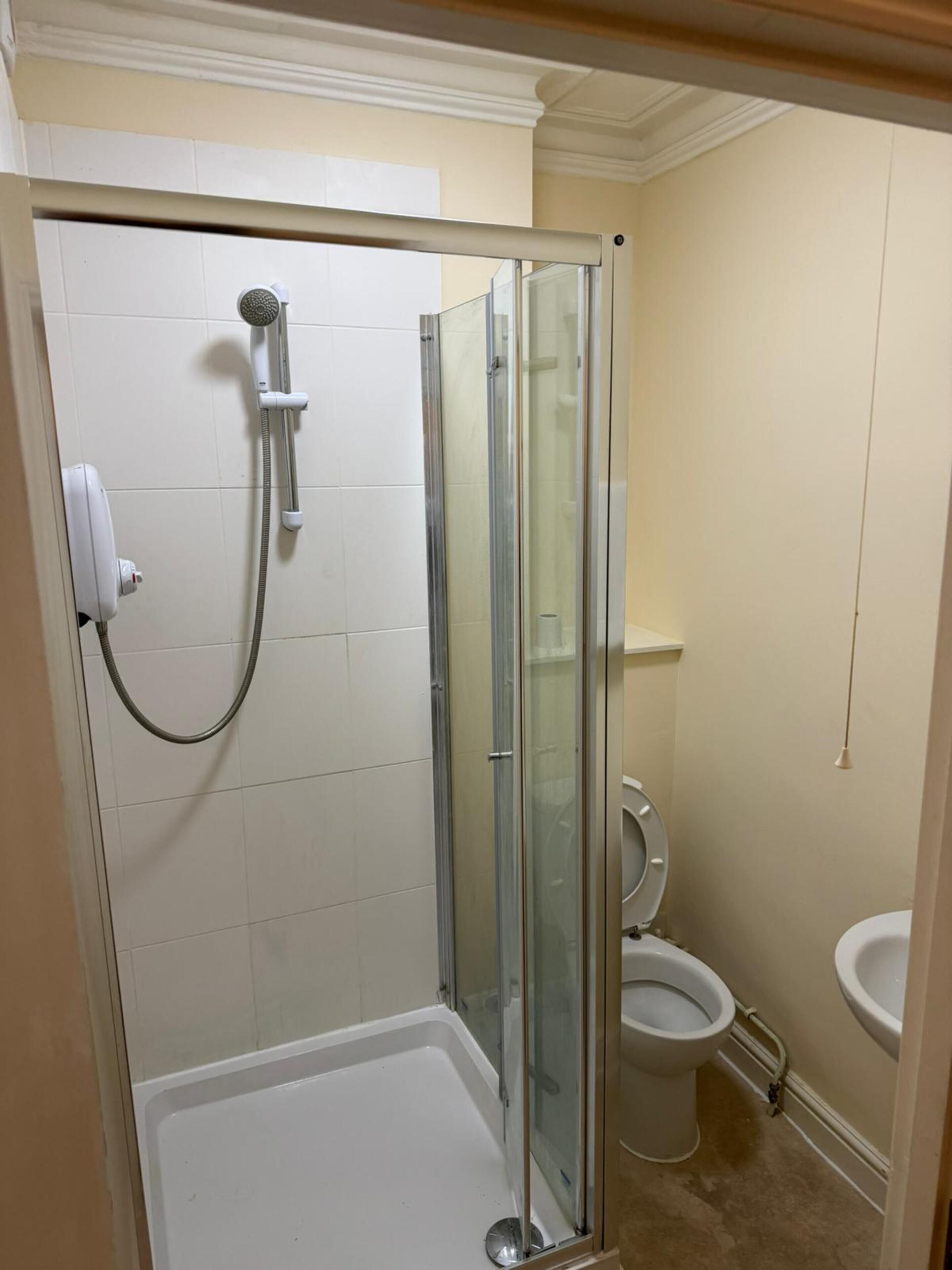 Un baño con ducha de vidrio, inodoro y lavamanos.