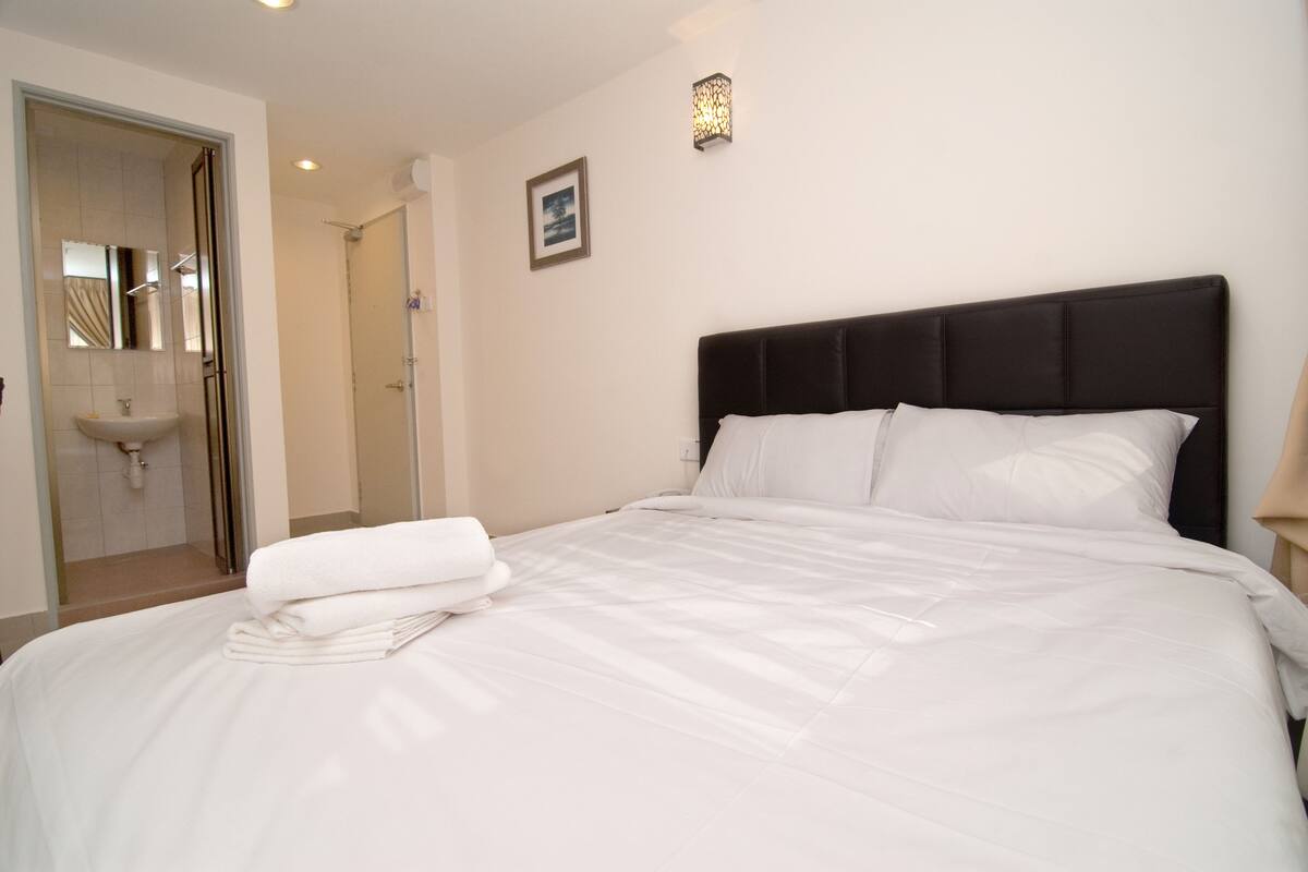 A hotel room with a bed, a bathroom, and a nightstand.