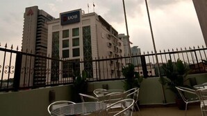 A hotel with a UOB sign, outdoor seating area with metal chairs and tables, and a view of the cityscape in the background. - Hotel A-One (Kuala Lumpur)