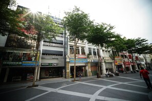 Vista de una calle con un hotel llamado 'HOTEL A-ONE' y diversas tiendas.