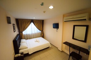 Una habitación de hotel con cama, escritorio, televisor y aire acondicionado.