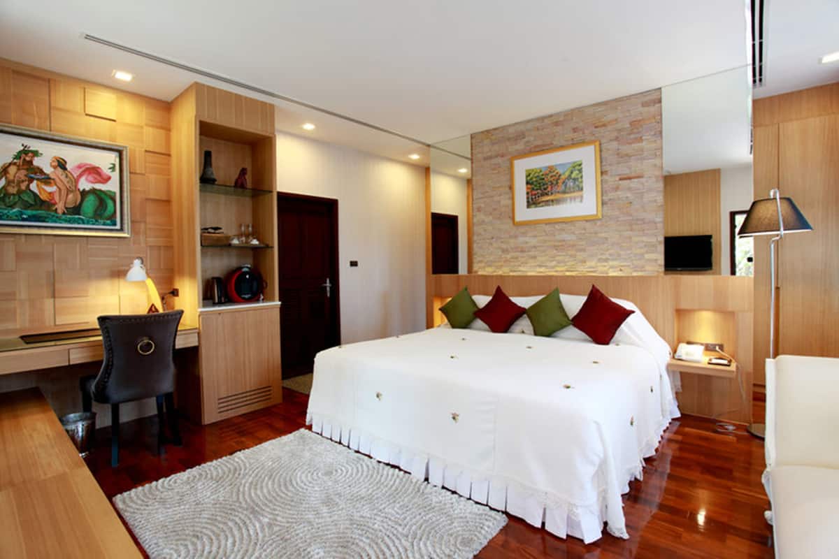 Een moderne hotelkamer met een groot bed, een bureau en een stoel. Er hangt een schilderij aan de muur en aan de andere kant staat een televisie.