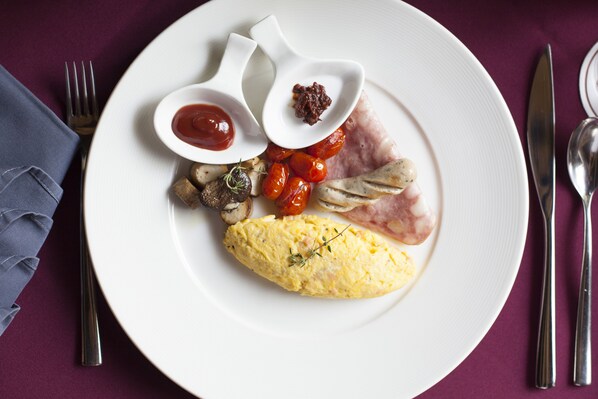 A plate with an omelette, cherry tomatoes, mushrooms, and ham, accompanied by two small bowls of sauce. - Sireeampan Boutique Resort & Spa (Chiang Mai)