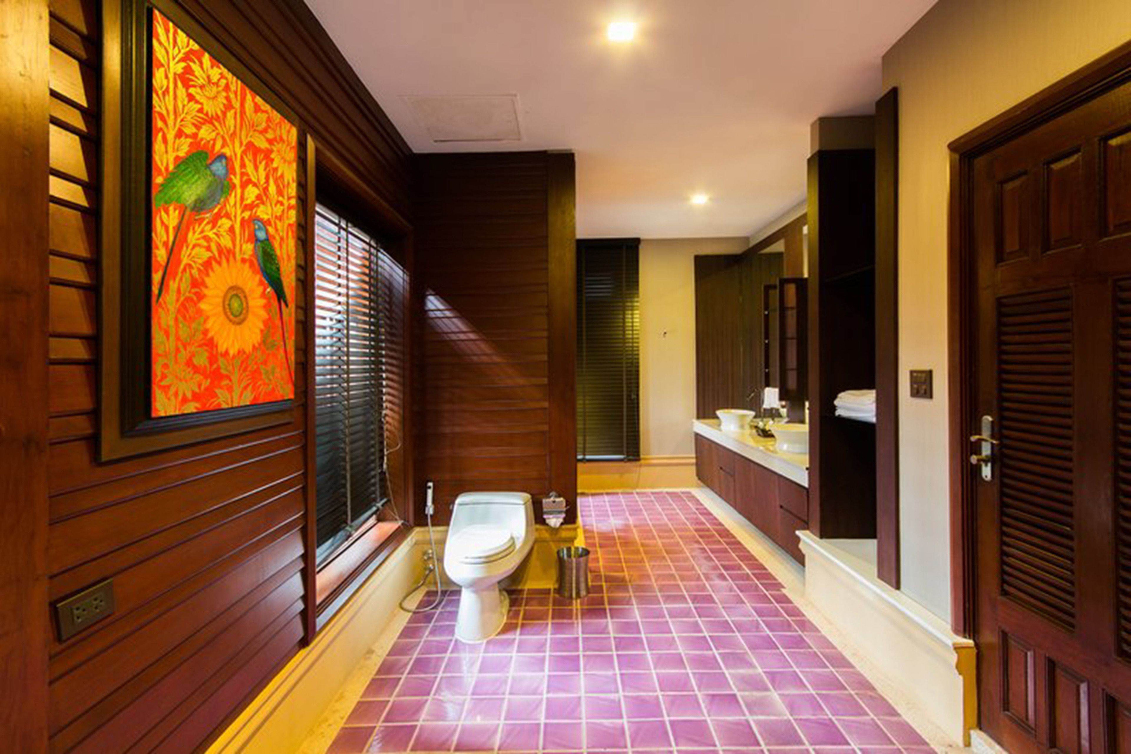 Ein Hotelbadezimmer mit Holzvertäfelung, einer Toilette, einem Waschbecken und einem großen Spiegel.
