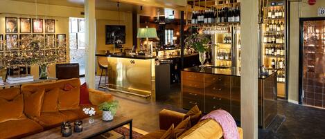 Un moderno vestíbulo de hotel con una zona de estar, un bar y una exhibición de vinos.