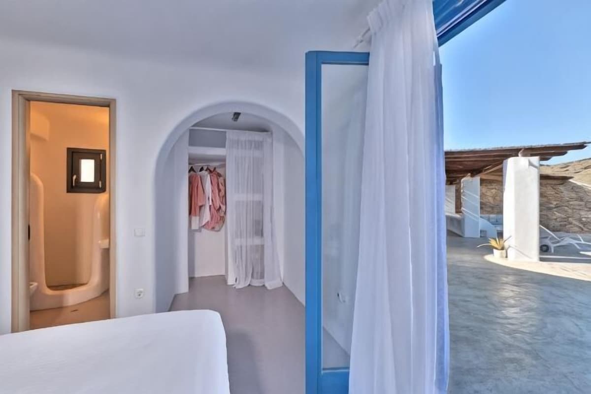 Quarto de hotel com cama, banheiro e vista para o exterior.