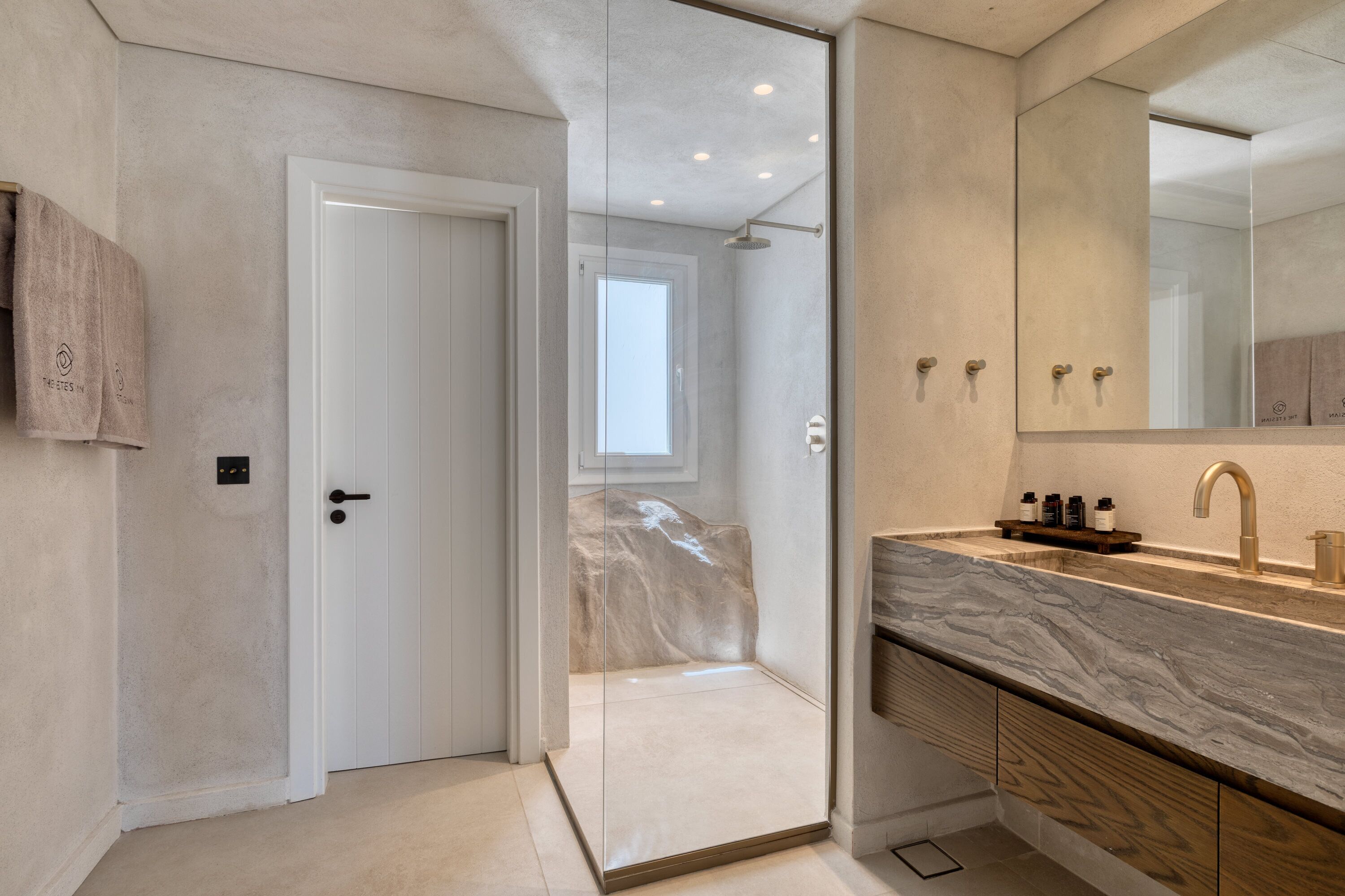 A modern bathroom with a glass shower enclosure, a marble sink, and a large mirror.