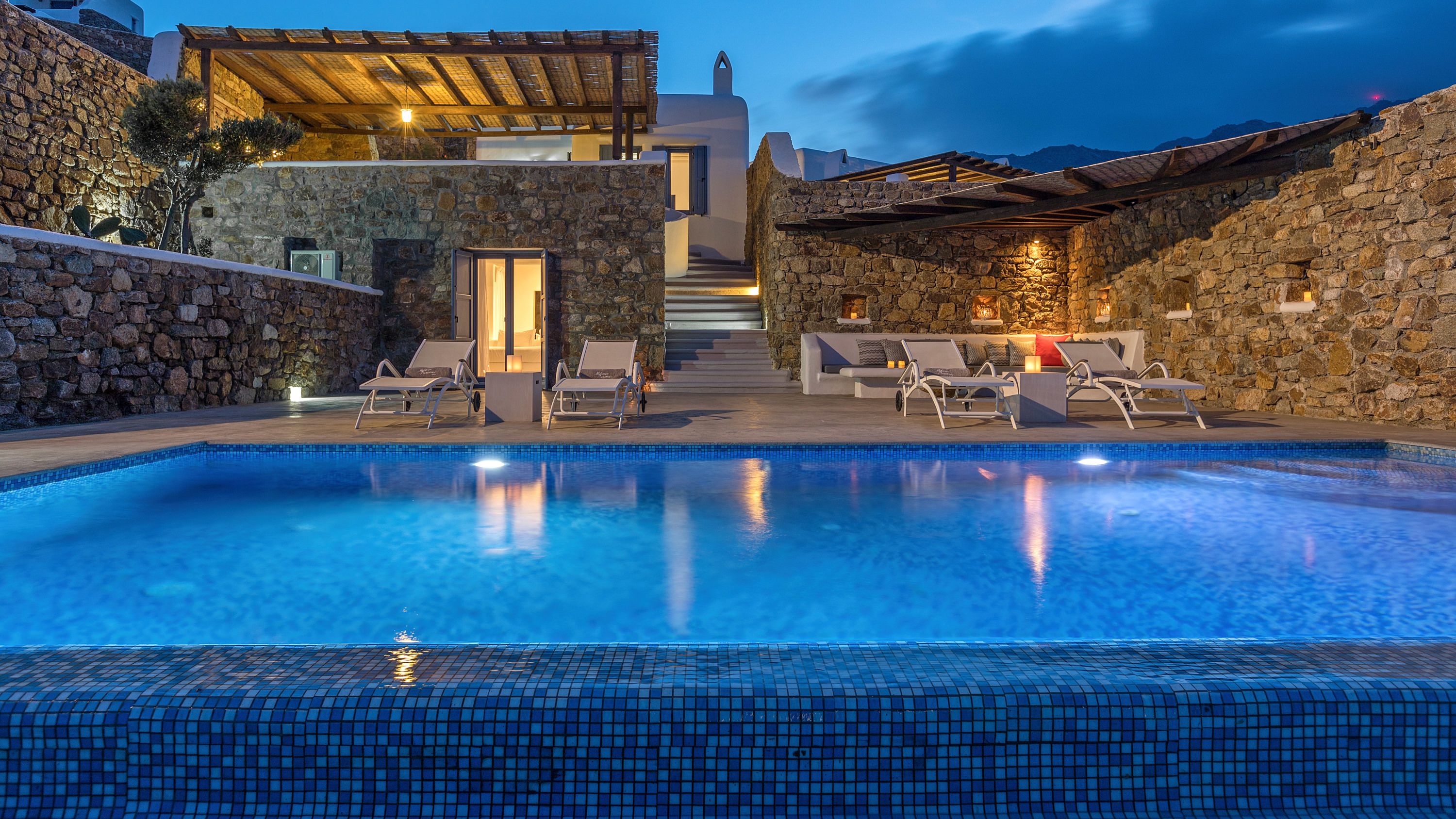 Une piscine avec des chaises longues et un mur en pierre.