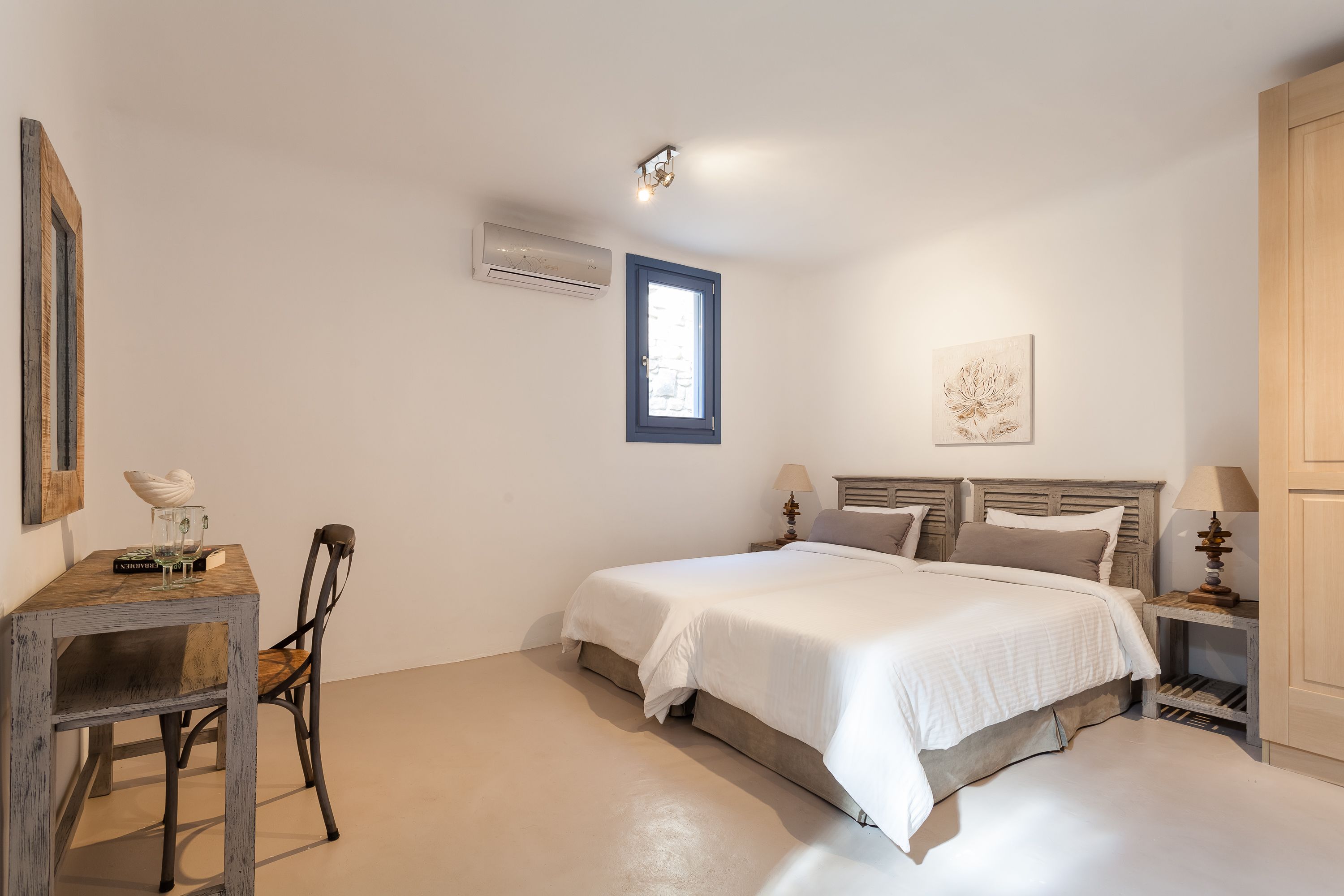 Ein Schlafzimmer mit Bett, Stuhl, Tisch, Fenster und Klimaanlage.
