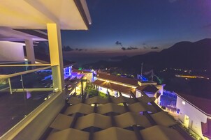 A staircase leading to a balcony with a view of a building and mountains in the distance.