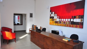 A reception area with a wooden desk, two red chairs, a large abstract painting, and a telephone. - Comfort@15 Hotel Colombo (Colombo)