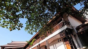 A two-story building with a balcony, surrounded by greenery and a clear sky. - Villa Korbhun Khinbua (Chiang Mai)