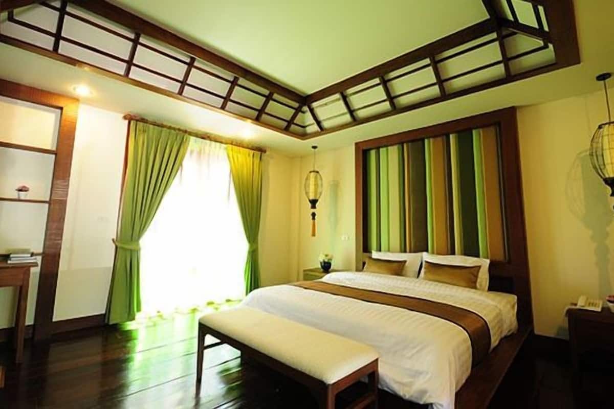 A bedroom with a large bed, a desk, and a window with curtains.