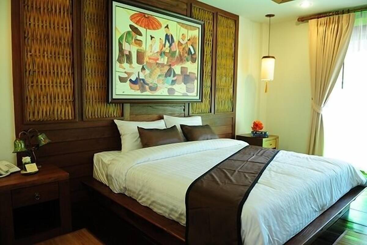 A hotel room with a bed, a nightstand, a painting, and a window with curtains.