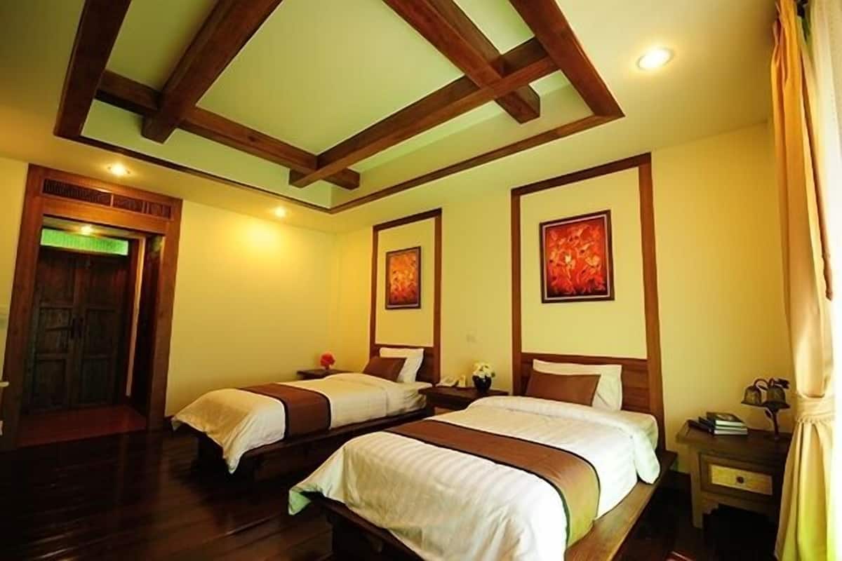 A hotel room with two beds, wooden beams on the ceiling, and artwork on the walls.