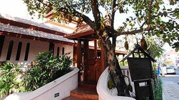 Traditional building with a covered entrance and staircase, surrounded by lush greenery and a small garden.