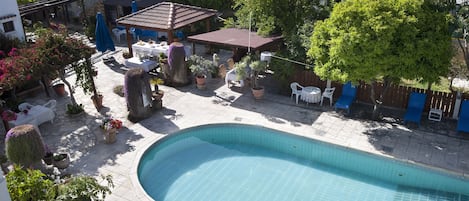 Une piscine dotée d’une terrasse carrelée, entourée de plantes en pot et de mobilier d’extérieur.