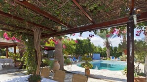 An outdoor patio with a pool, covered seating, and potted plants. - Follow The Sun (Polis)