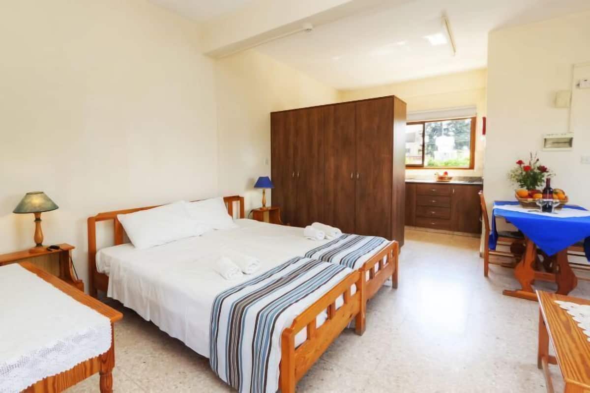 Quarto com cama, mesa de cabeceira, abajur, guarda-roupa e vista para a cozinha.